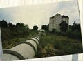 Blick über den verwilderten, heute überbauten <!--LINK'" 0:10-->, im Hintergrund das Gebäude <!--LINK'" 0:11-->, im Vordergrund der kanalisierte <a class="mw-selflink selflink">Poppenreuther Landgraben</a> im Juli 1997