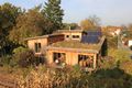 Holzhaus mit Dachbegrünung (Außenwand aus unbehandeltem Lärchenholz in Ständerbauweise, Wärmedämmung aus eingeblasenen Hobelspänen, Innenwände aus Lehmputz auf Schilfrohrplatten; Heizung und Warmwasserbereitung durch Grundofen und Sonnenkollektoren; weitgehend in Eigenleistung durch <!--LINK'" 0:16--> erbaut.)