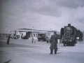 Ein Güterzug quert die [[Würzburger Straße]] mit zwei Streckenposten (1950er Jahre)