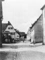 Blick in die kopfsteingepflasterte <a class="mw-selflink selflink">Brückenstraße</a> mit Kriegerdenkmal und Gebäude dahinter <!--LINK'" 0:74--> und 2, Gebäude rechts <!--LINK'" 0:75--> und 1 dahinter, im Hintergrund <!--LINK'" 0:76-->, 1936