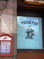 Gaststätte Texas Pub 2011 als das Rauchverbot in Wirtshäusern in Kraft trat. Die Zigarette im Mund des Cowboys ist durchgestrichen.