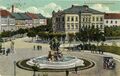 Blick auf den Bahnhofplatz mit Centauren-Brunnen - inkl. der Fotomontage eines zeitgenössischen PKWs ins Bild, gel. 1913