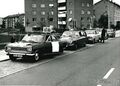Autos mit Großplakaten auf dem Dach und einem großen Lautsprecher während des Autokorsos zum Volksentscheid "Wählen mit 18" 1970. Im Hintergrund das Hochhaus Espanstr. 8