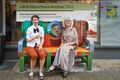 Jakob-Wassermann-Bank gemeinsam mit den beiden Künstlerinnen vor dem Bonakdar Teppichkultur Geschäft in der Fußgängerzone, 2023